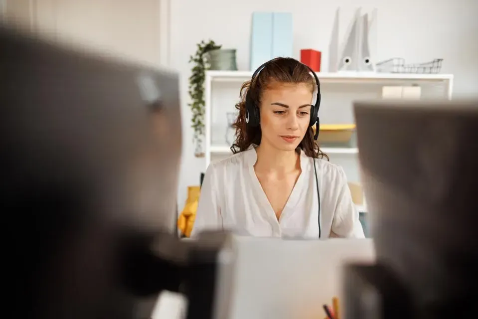 A woman wearing headphones is sitting in front of a laptop computer.
