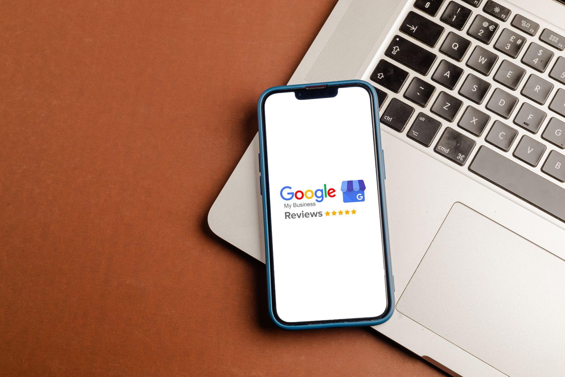 Google search screen on a smartphone beside a laptop on a brown desk.
