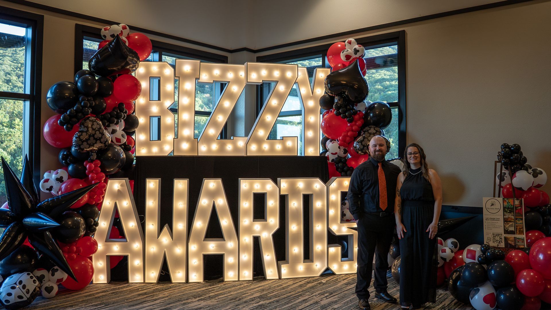Marty Awards stage with large lit letters, red and black balloon decor, and two people posing nearby