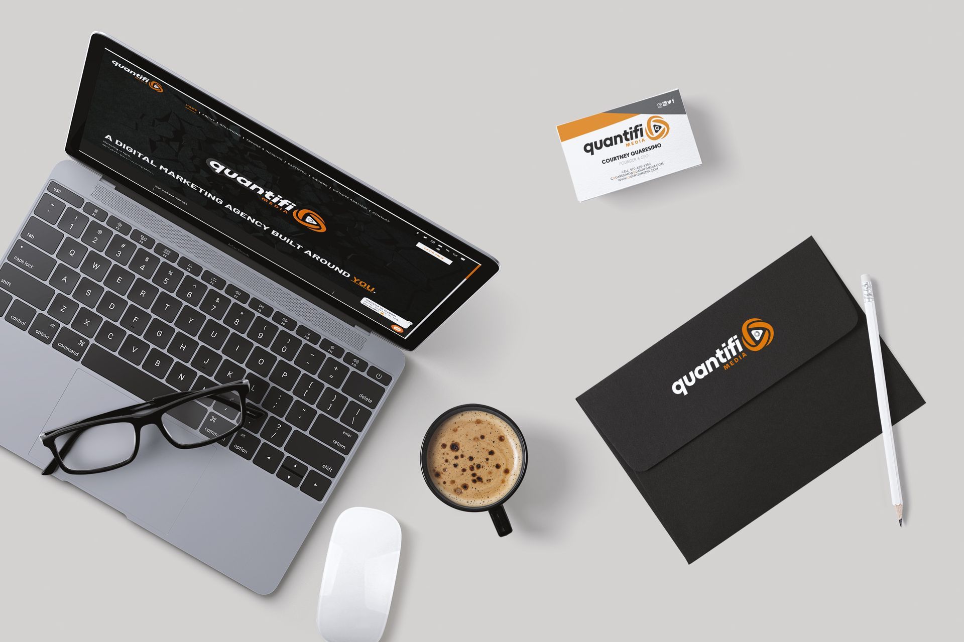 A laptop is open on a desk next to a cup of coffee and a business card.