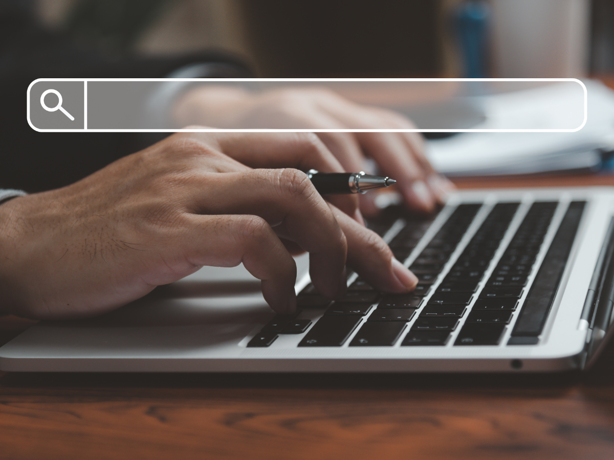 Person typing on laptop with search bar overlay. Person typing on laptop with search bar overlay.