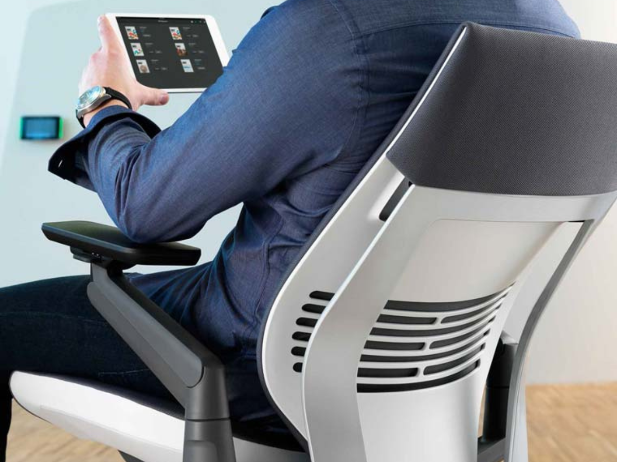 A man is sitting in an office chair holding a tablet