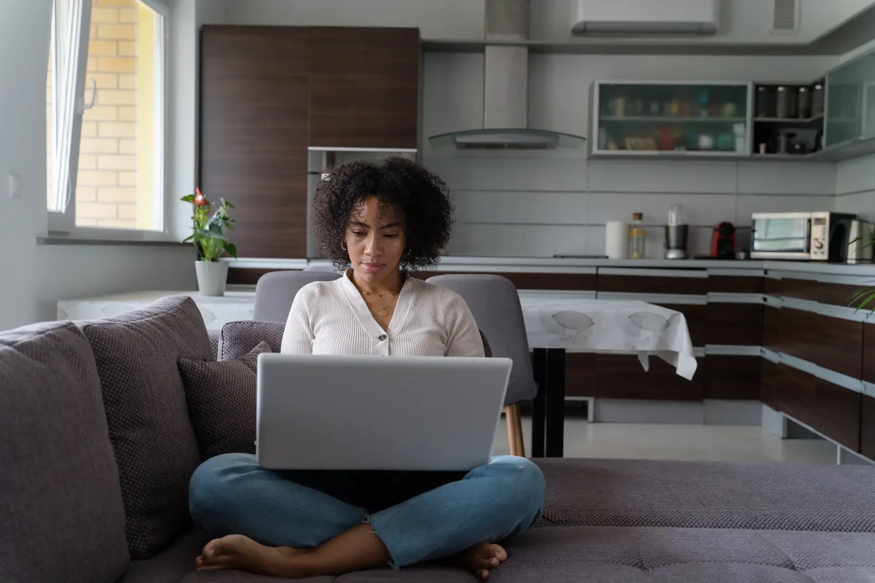 A woman is sitting on a couch using a laptop computer.