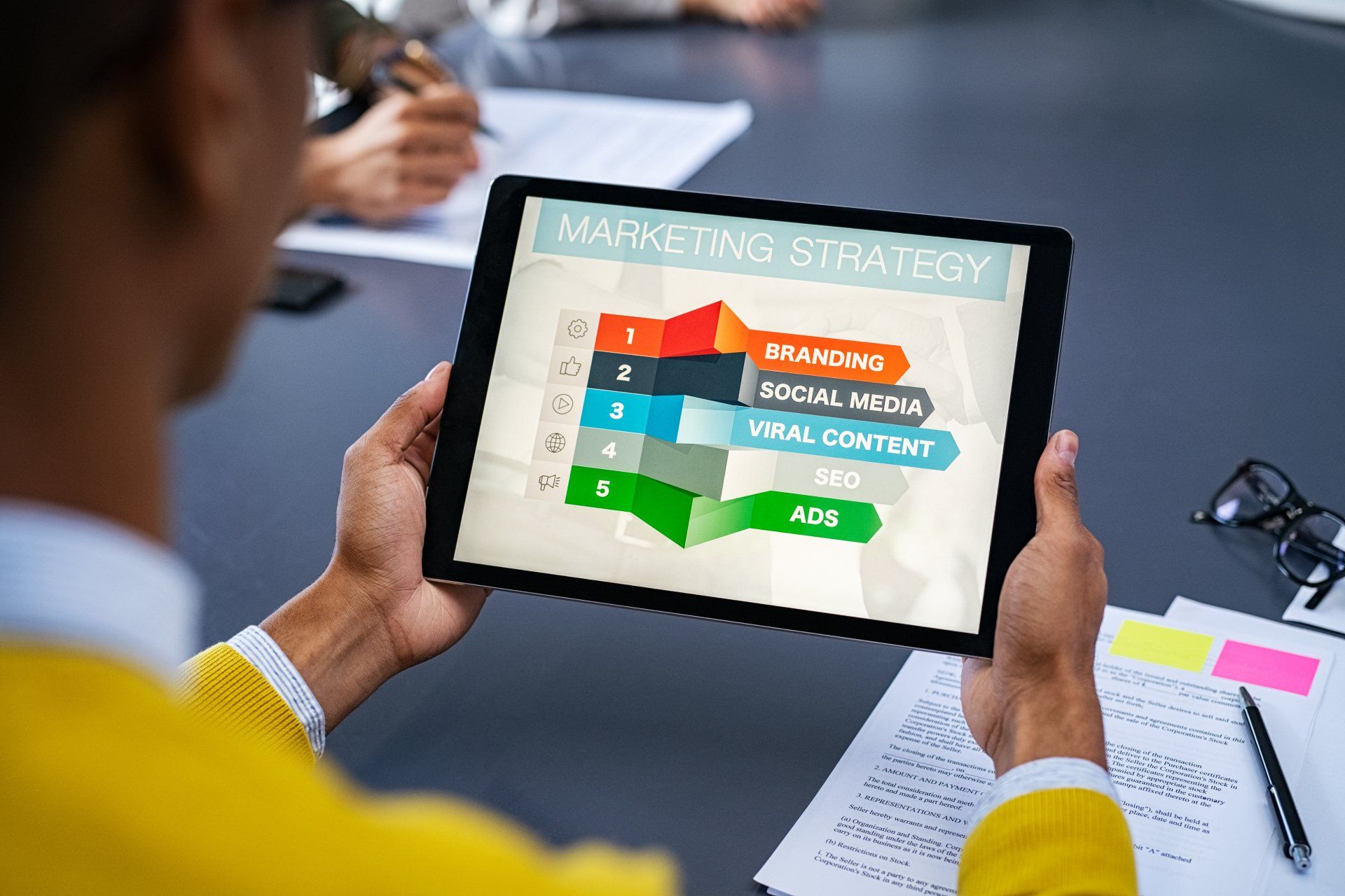A man is holding a tablet with a marketing strategy on it.