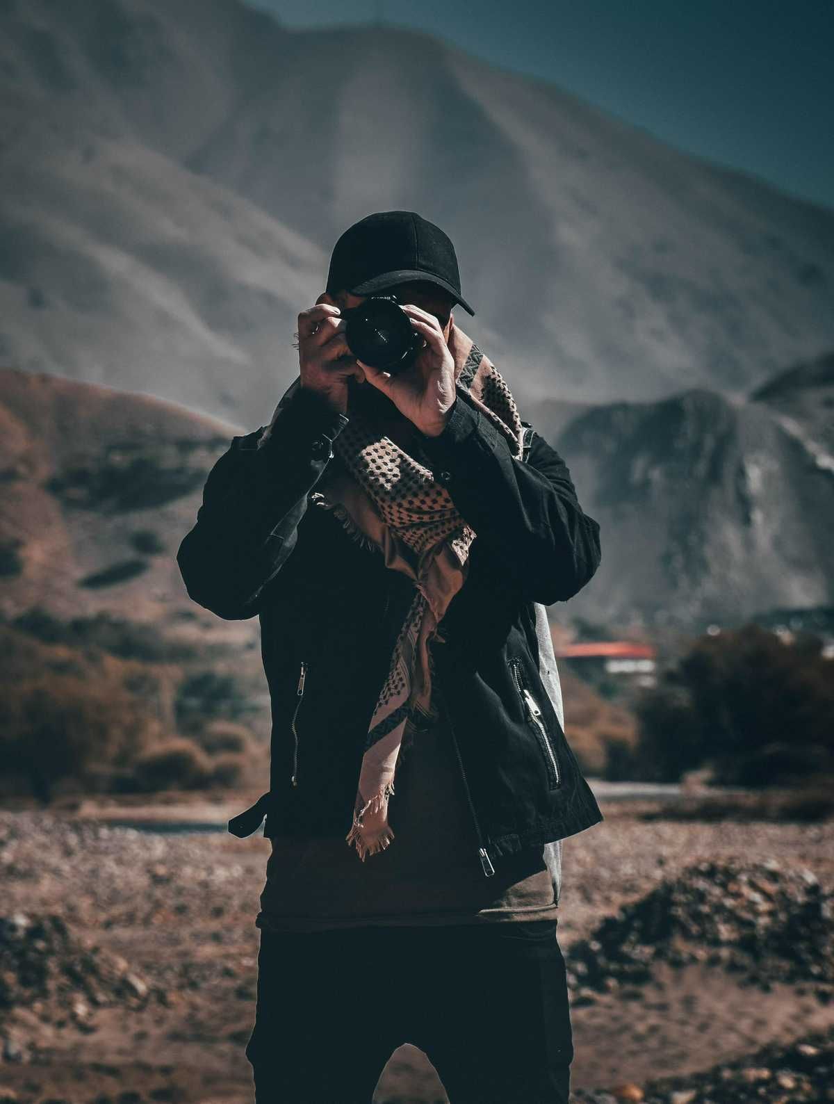 A man is taking a picture of a mountain with a camera. A man is taking a picture of a mountain with a camera.