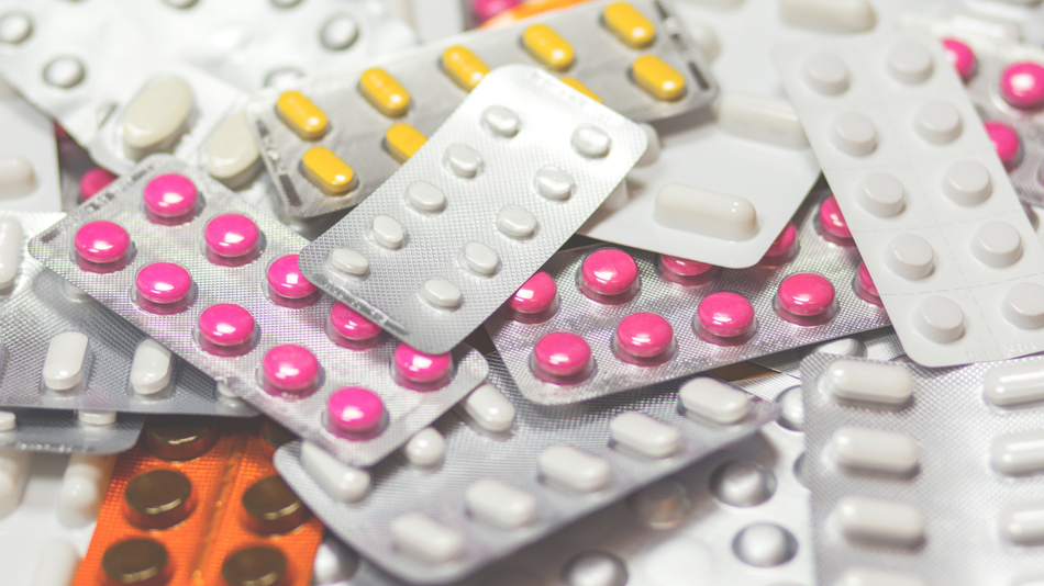 Assorted blister packs of colorful pills and capsules scattered in a close-up.