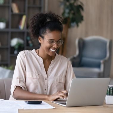 Smiling woman typing on a laptop at a desk in a bright office
