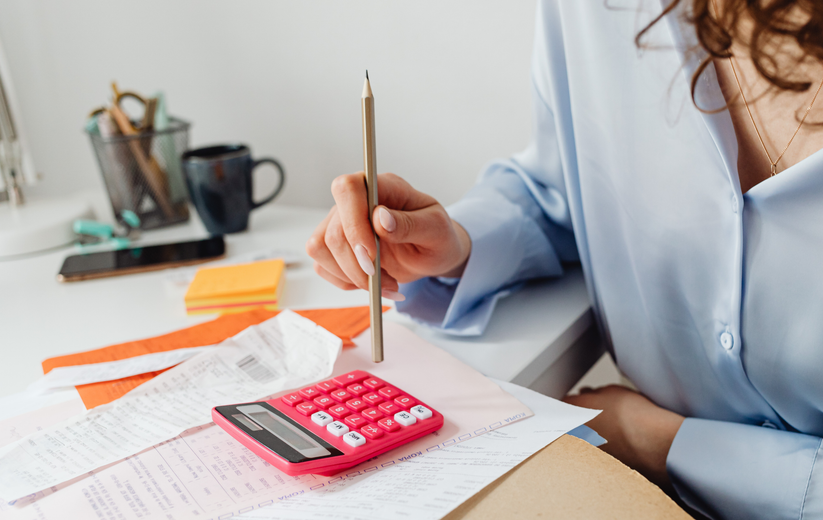 Person using a pencil and calculator to review paperwork at a desk
