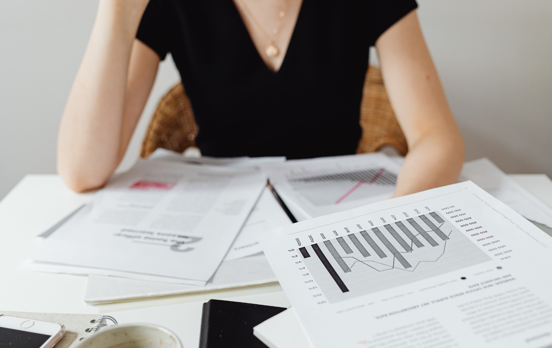 Person reviewing documents with charts and reports on a desk.