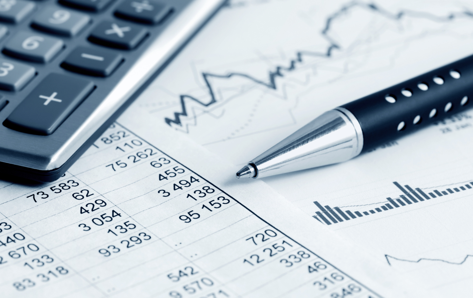 Calculator, pen, and financial charts on a desk, showing business analysis and accounting.