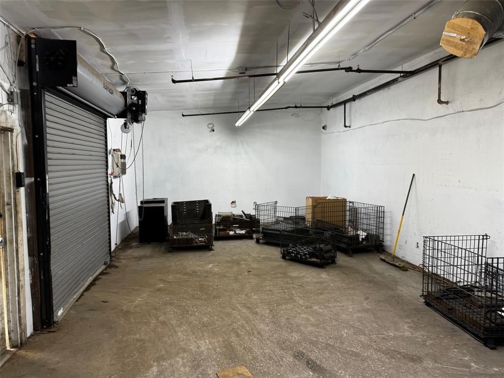 An empty warehouse with a garage door and a lot of crates.