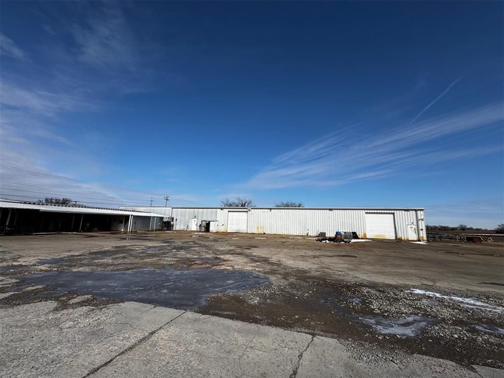 A large white building is sitting in the middle of a dirt field.