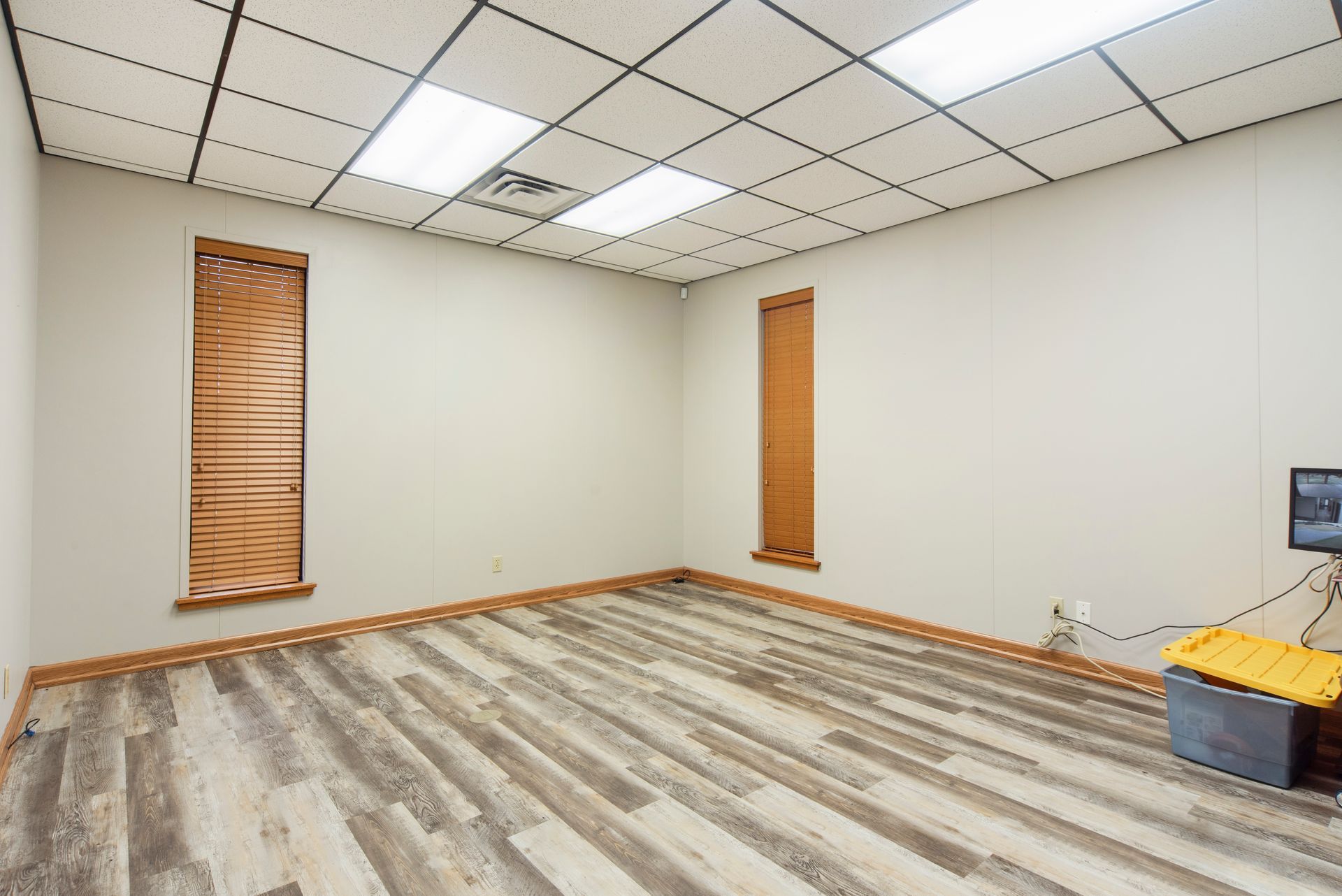 A large empty room with a wooden floor and two windows.