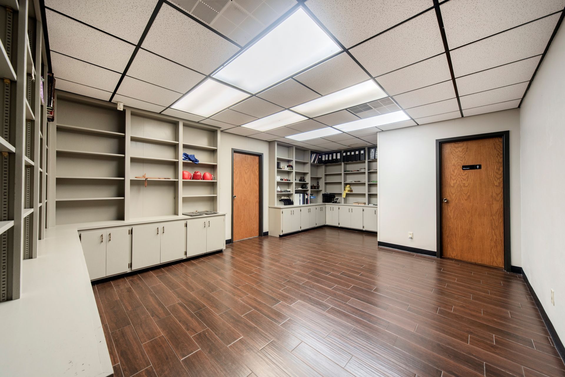 A large empty room with wooden floors and shelves.