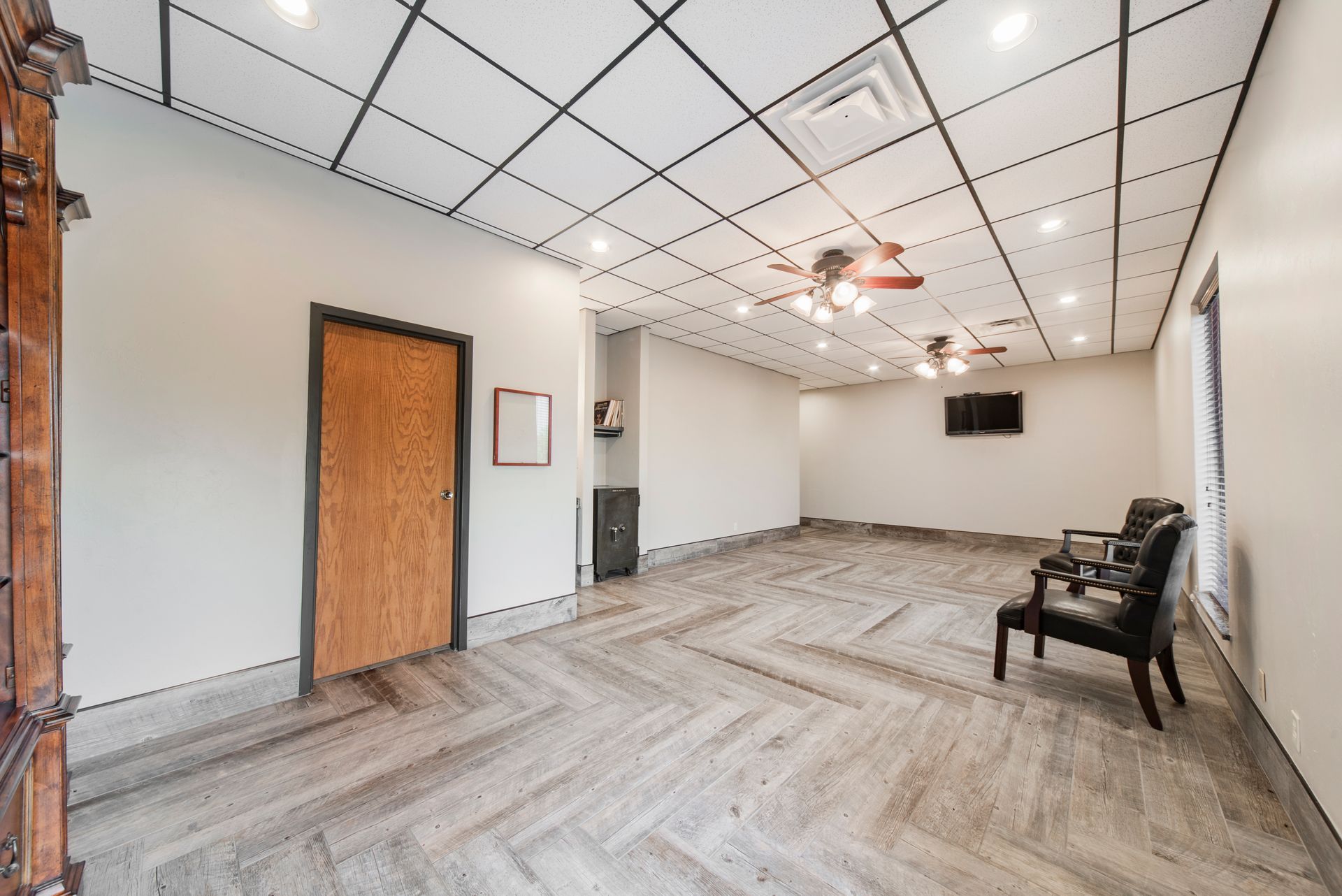 A large empty room with a ceiling fan and chairs.