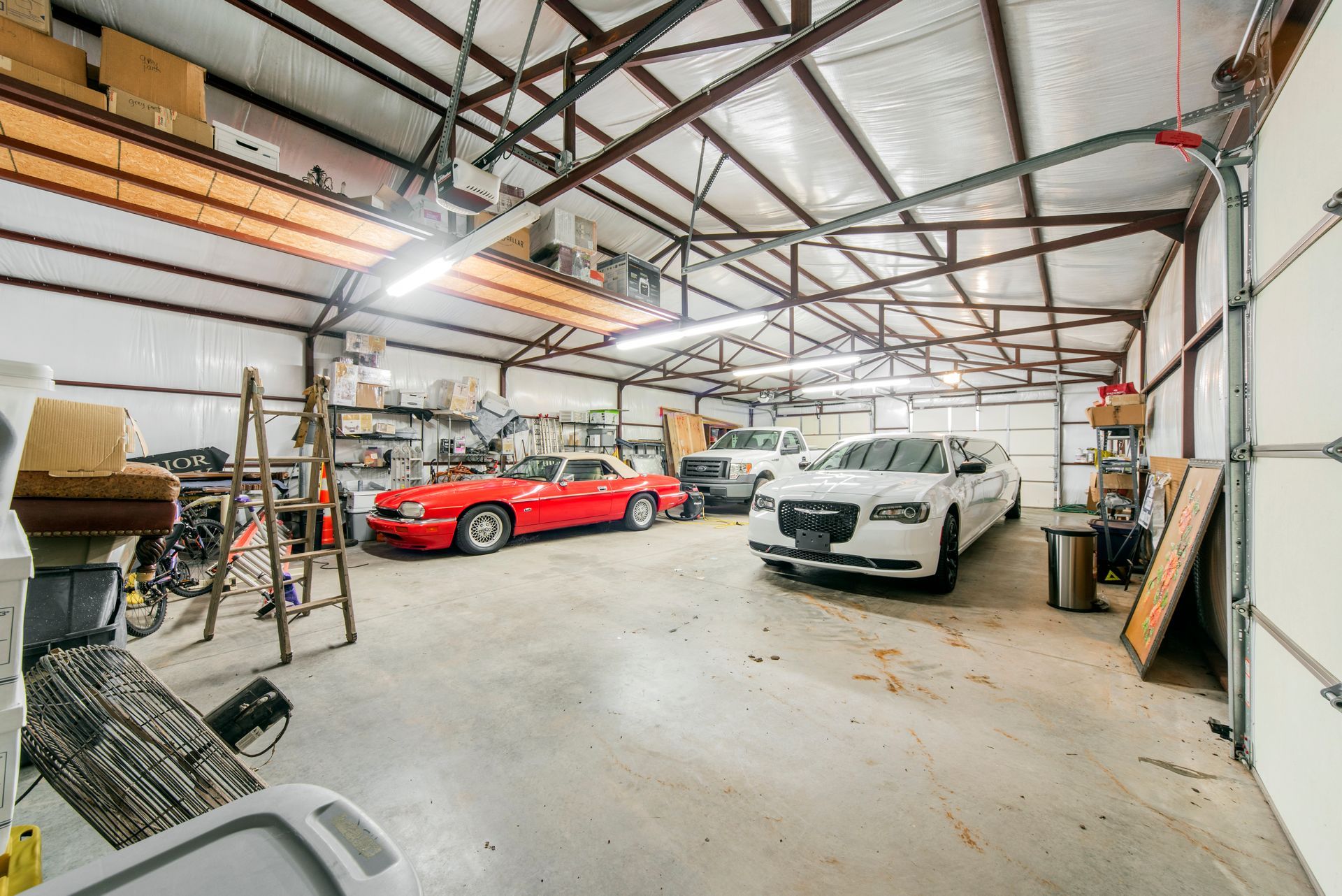 A garage with a red car and a white car parked in it.