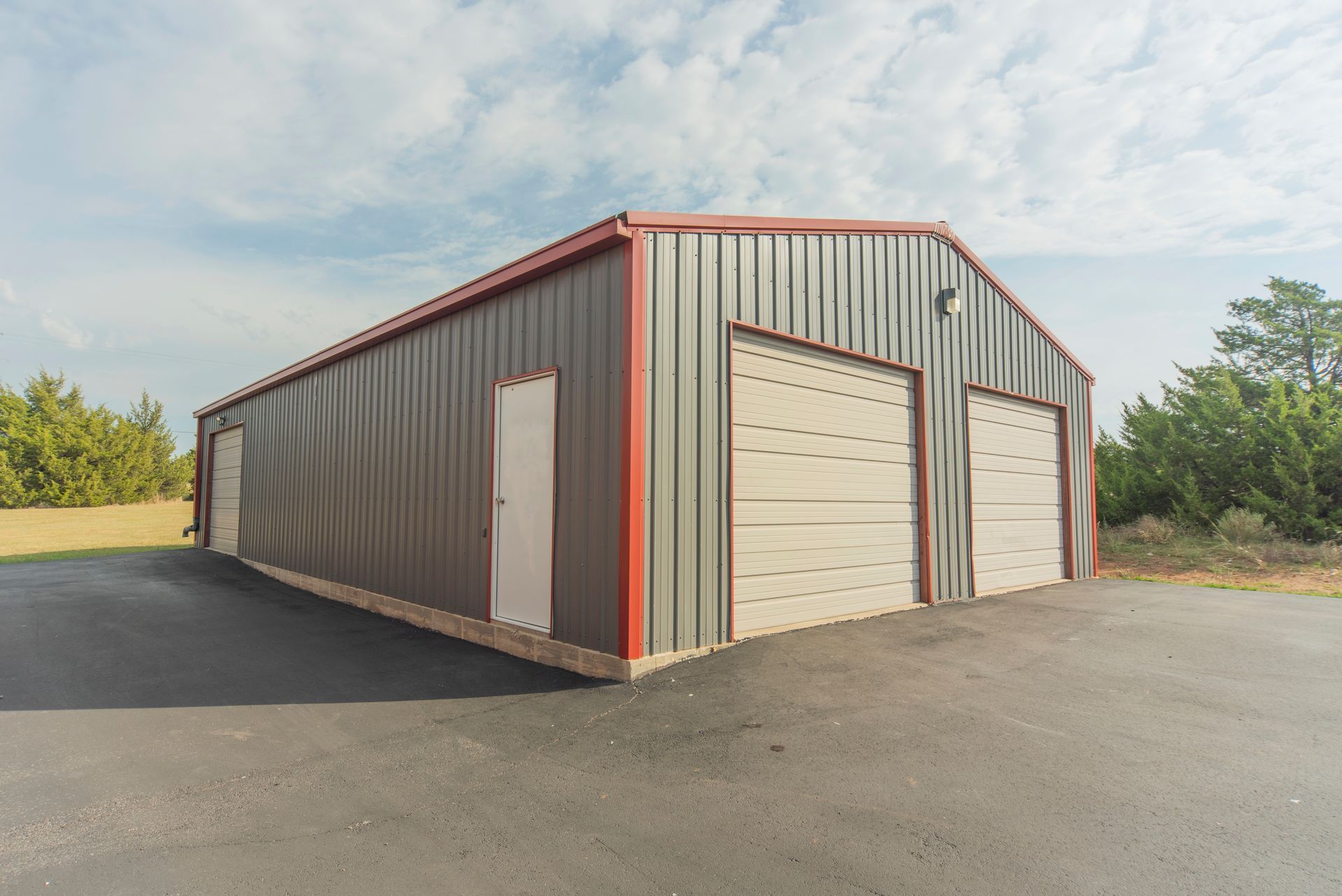 A large metal building with three garage doors and a driveway.