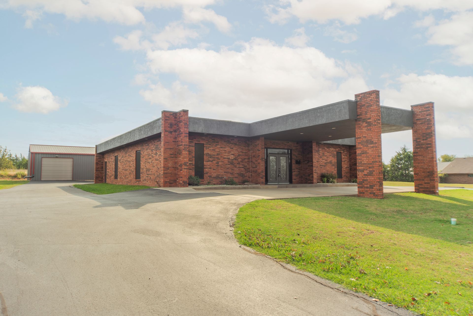 A large brick house is sitting on top of a lush green field.