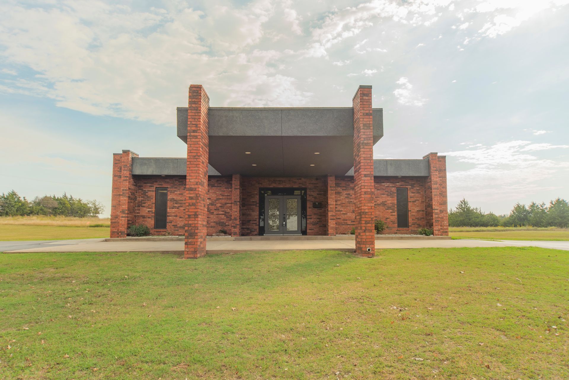 A large brick building is sitting on top of a lush green field.