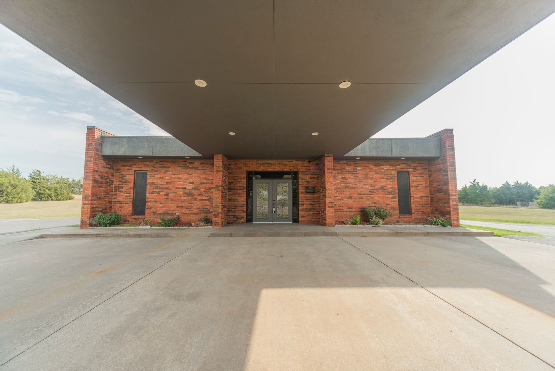 The front of a brick building with a parking lot in front of it.