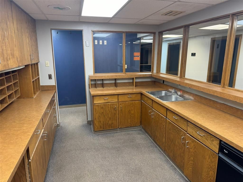 A long kitchen with wooden cabinets and a sink.