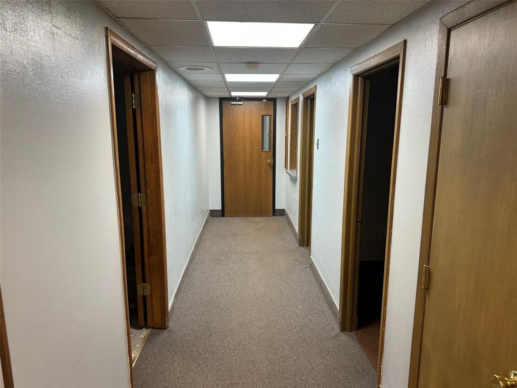 A long hallway with wooden doors and white walls