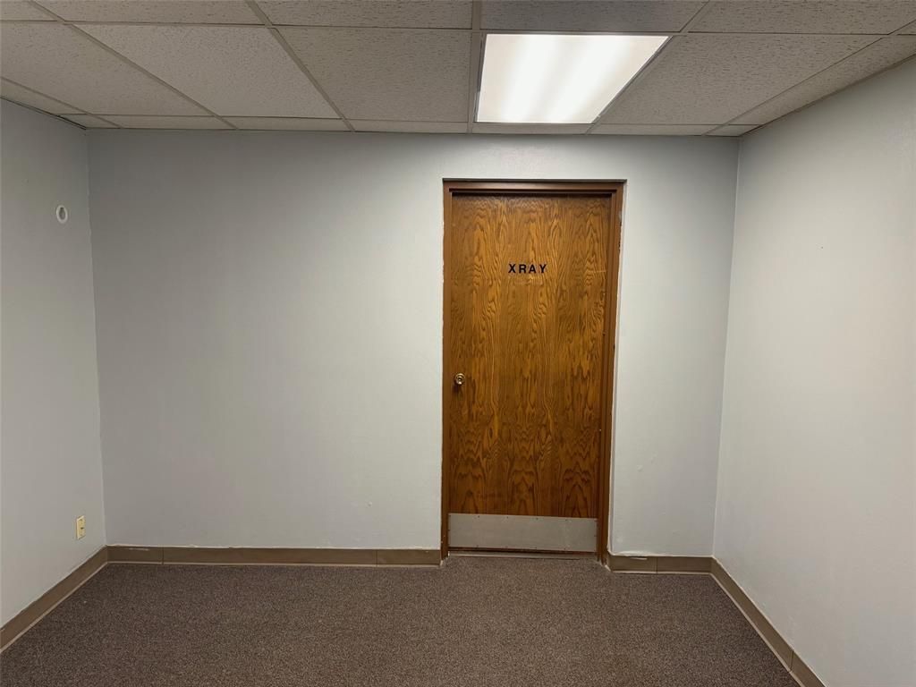 An empty room with a wooden door and a light on the ceiling.
