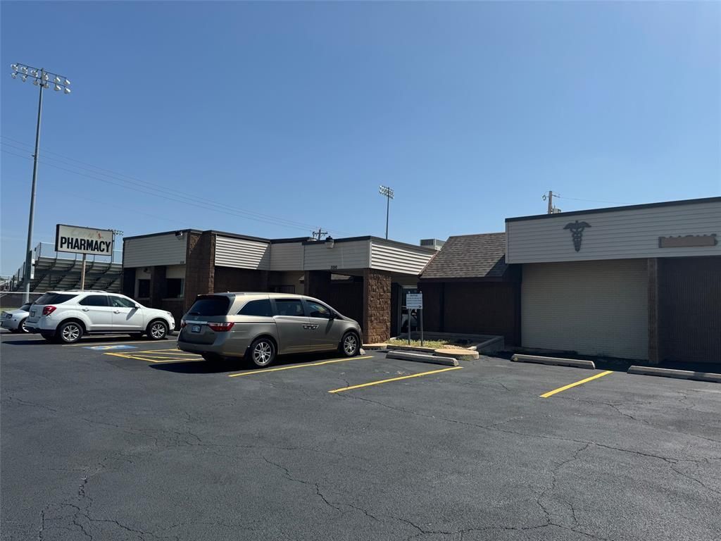 A row of cars are parked in a parking lot in front of a building.