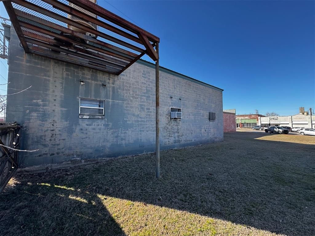 A brick building with a metal roof is sitting in the middle of a grassy field.