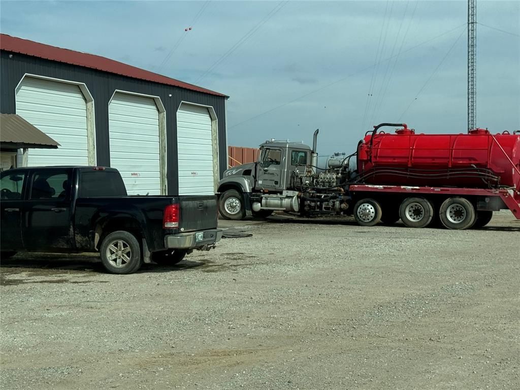 A black truck is parked next to a red vacuum truck