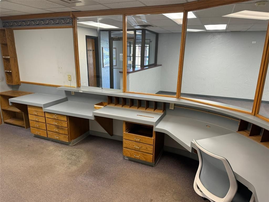 An empty office with desks and a large window.