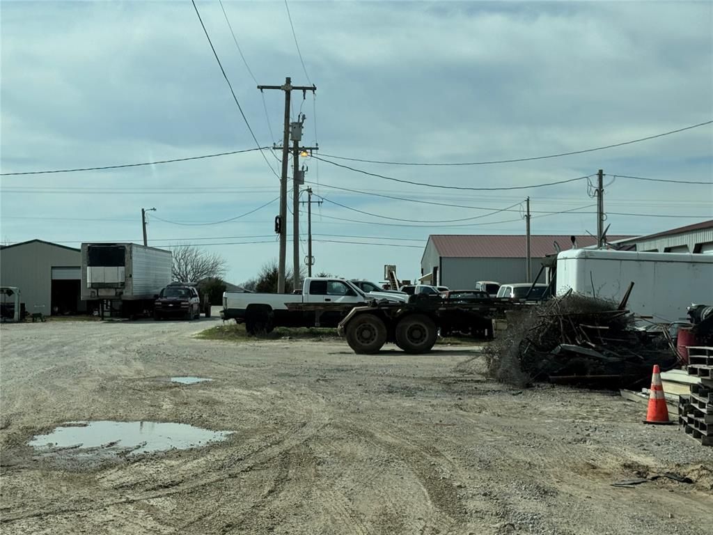 A lot of trucks are parked in a dirt lot.