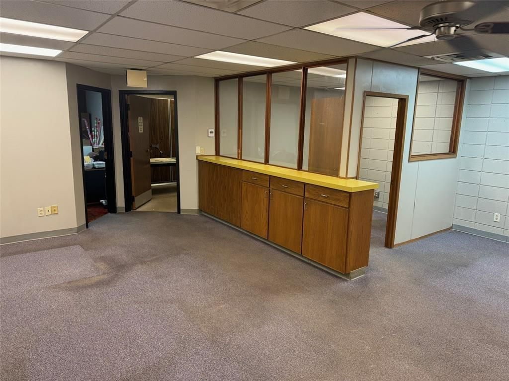 An empty room with a ceiling fan and a wooden cabinet.
