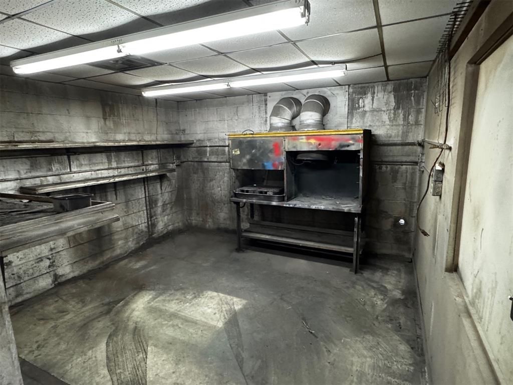 An empty room with a stove and a table in it.