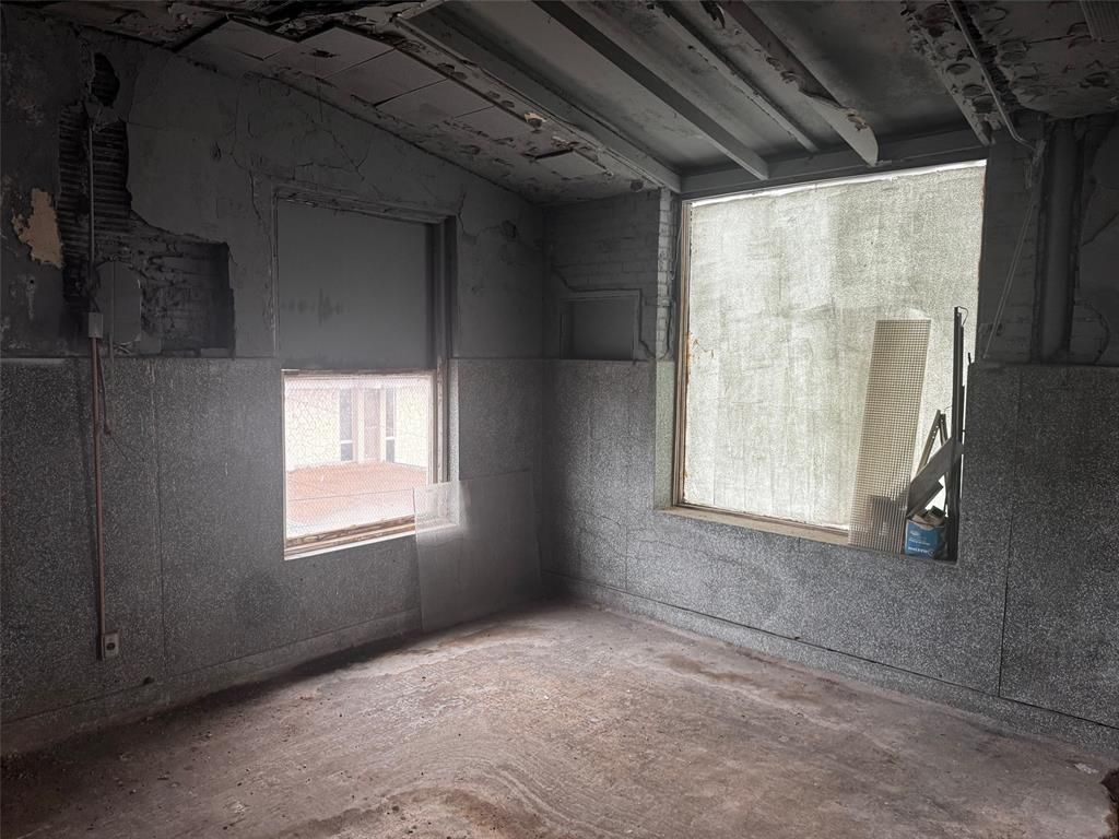 An empty room with two windows and a light coming through the window.