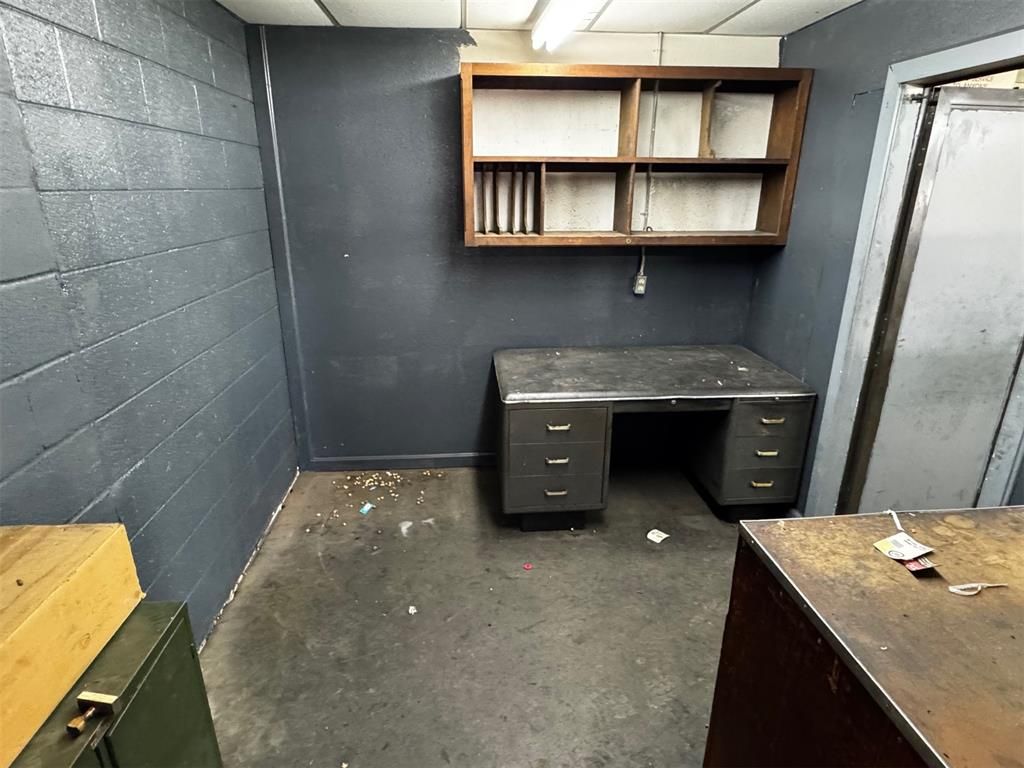 An empty room with a desk and shelves on the wall.