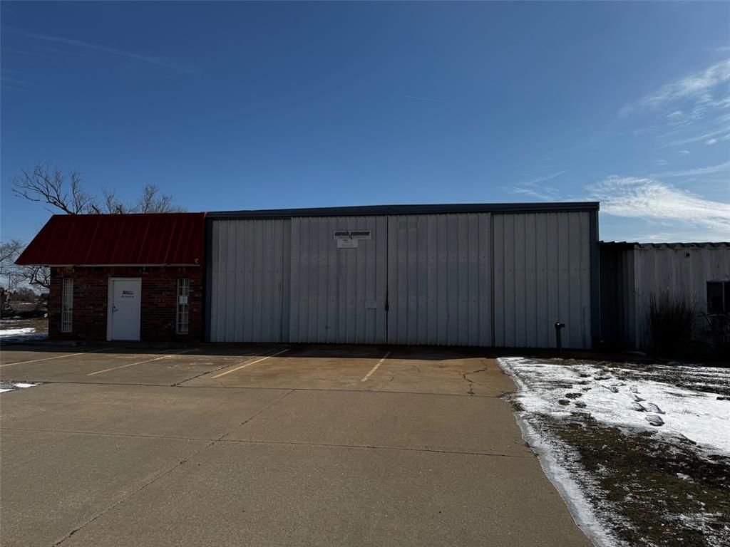 A large white building with a red roof is sitting in the middle of a parking lot.