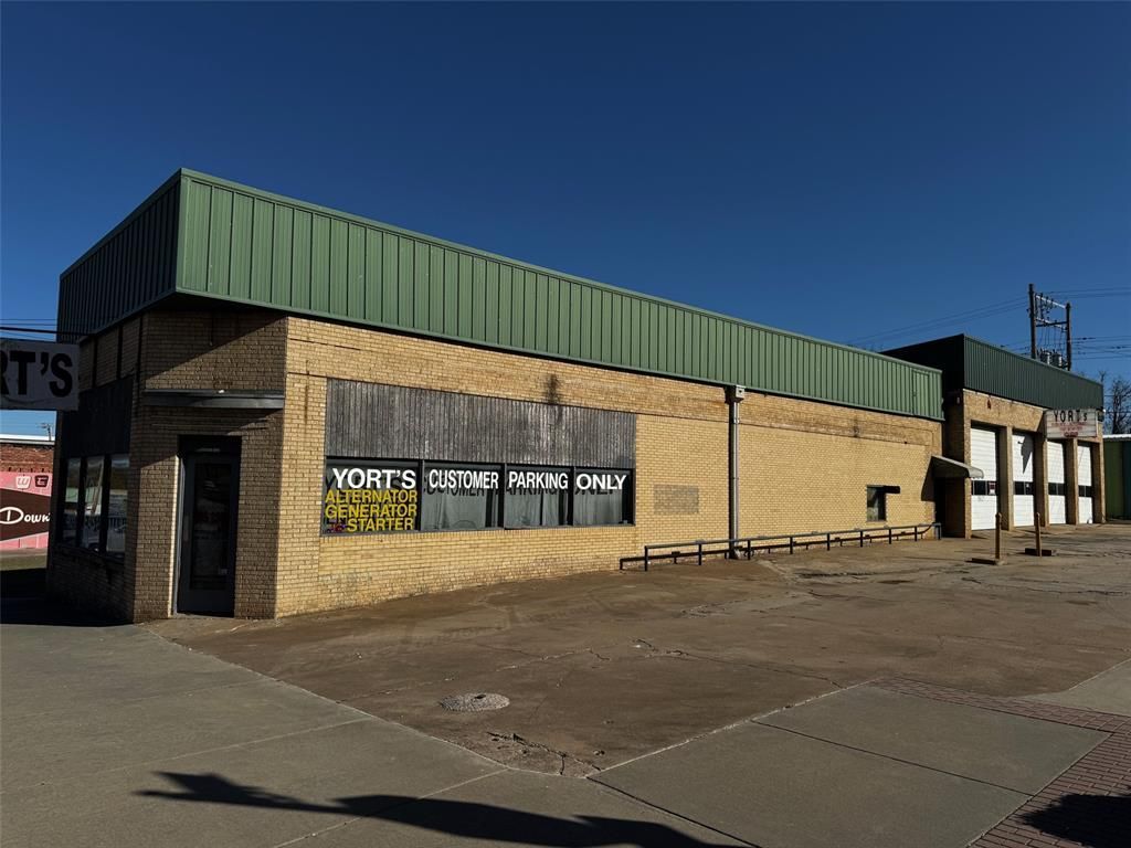 A large brick building with a green roof and a parking lot in front of it.