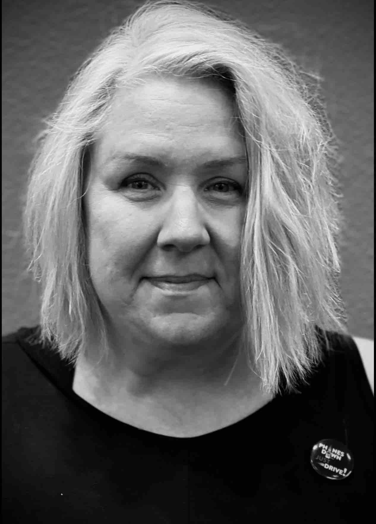 A woman with blonde hair is smiling in a black and white photo.