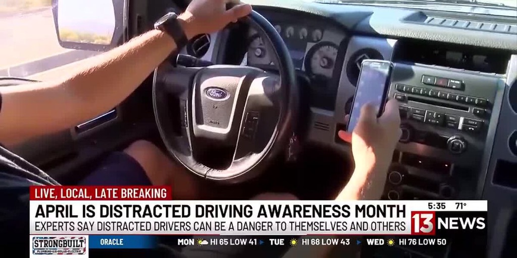A man is driving a truck with a cell phone in his hand.