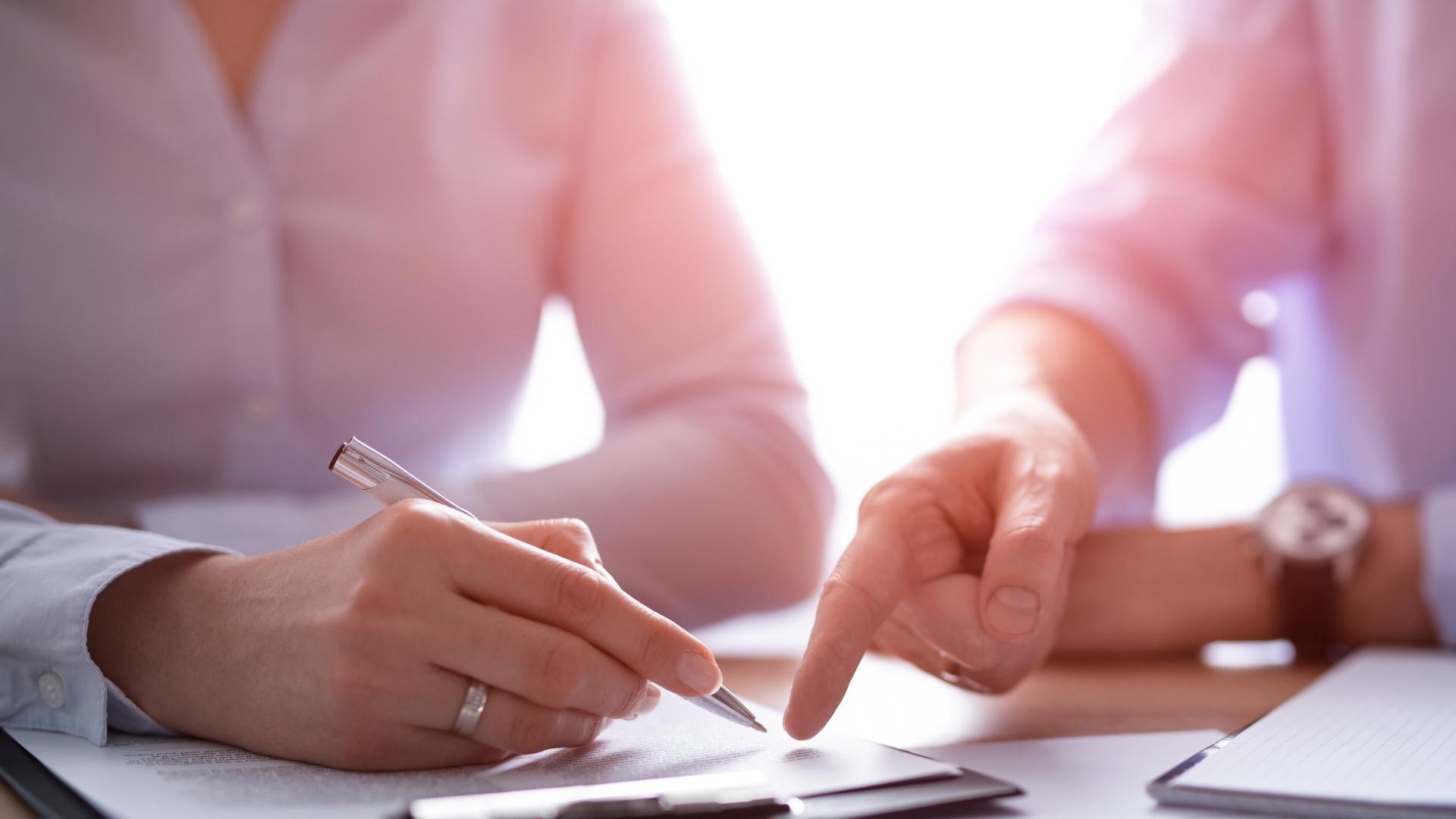 A man and a woman are sitting at a table writing on a piece of paper.