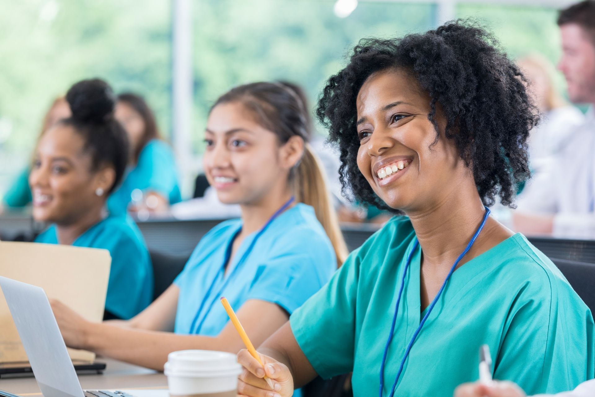 A group of nurses are sitting in a classroom with laptops.