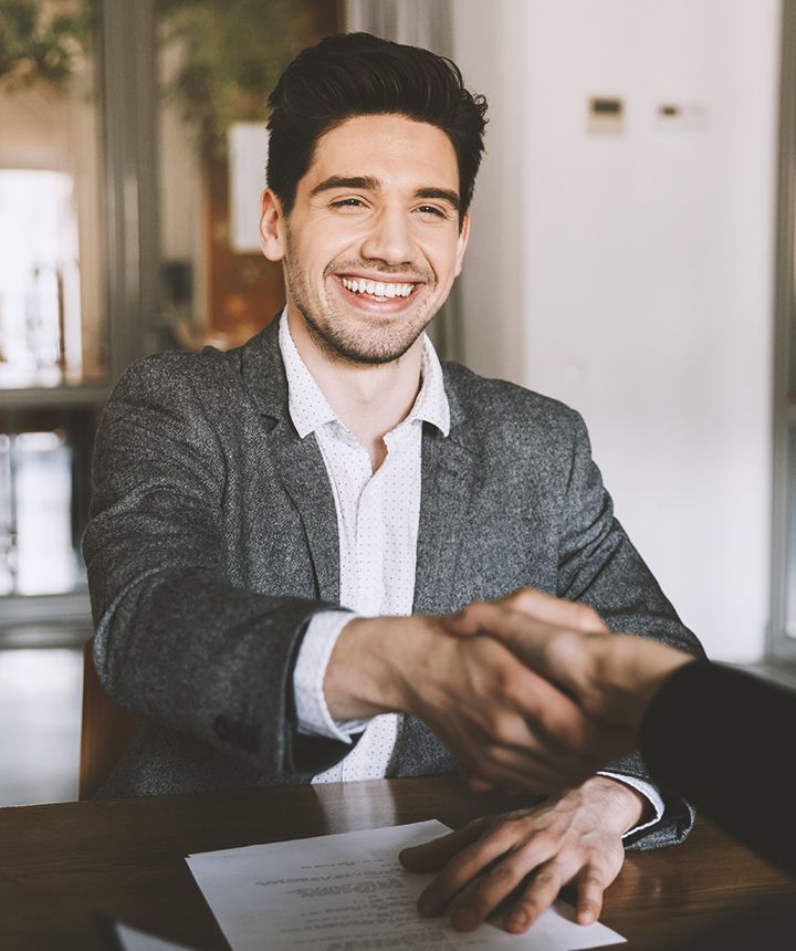 A man in a suit is shaking hands with another man at a table.