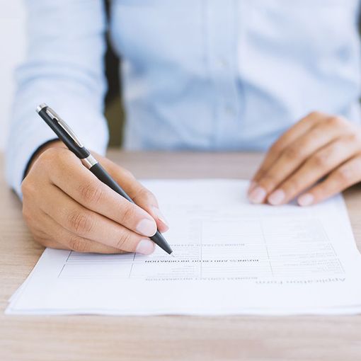 A person is writing on a piece of paper with a pen.