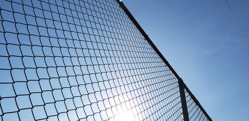 A chain link fence with the sun shining through it.