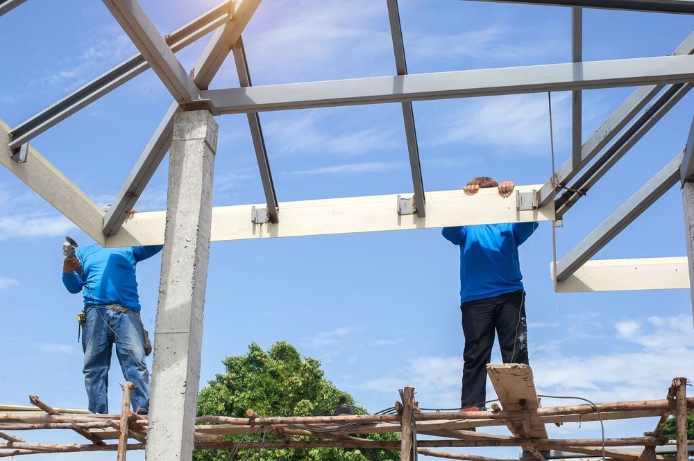 Two construction workers are working on a metal structure.