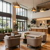 Modern hotel lobby with beige lounge seating, high windows, warm pendant lights, and a reception desk