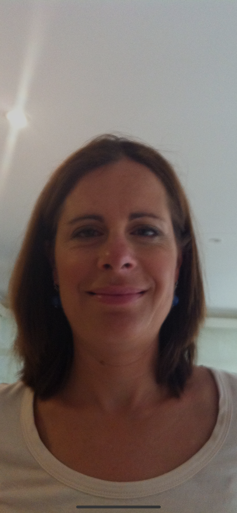 Woman with shoulder-length brown hair smiling against a plain light background