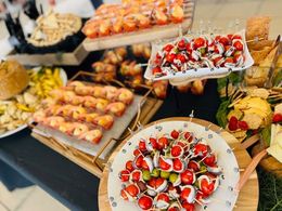 Dessert buffet with strawberry-topped pastries and fruit on tiered trays at a catering table