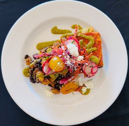 Colorful gourmet dish on a white plate with greens, pickled onions, and a bright egg yolk center
